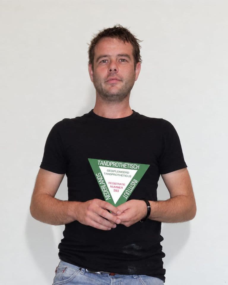 Thijs houdt het schild van het Nederlands Tandprothetisch Instituut vast: gediplomeerd tandprotheticus, registratienummer 593